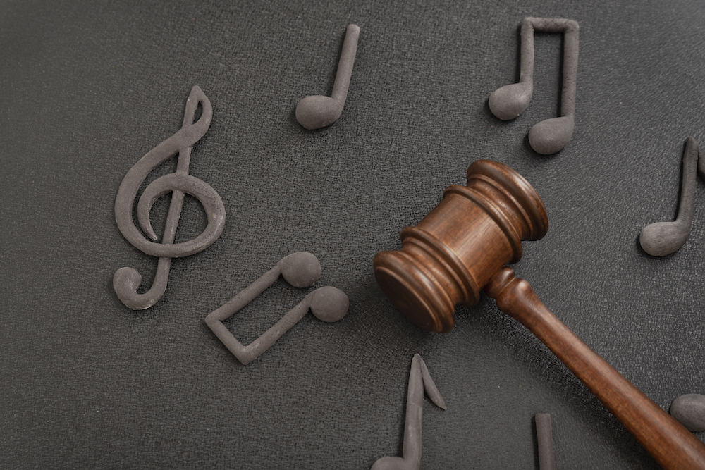 judges gavel surrounded by treble clef notes black background violation music license copyright music piracy